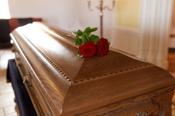 funeral and funeral concept - red rose flowers on a wooden box in the church