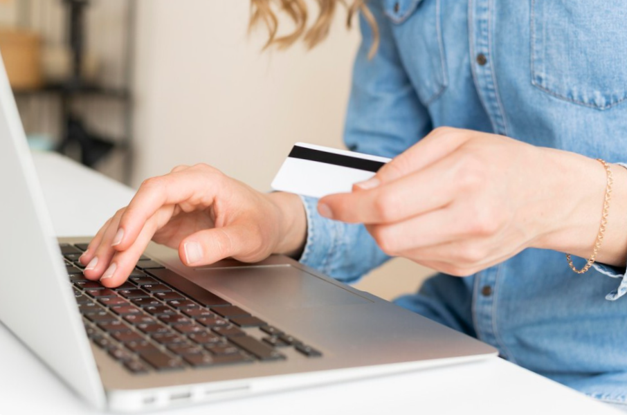 Close-up woman paying with credit card through laptop