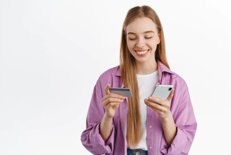 Smiling blond girl with smartphone and debit card in hands