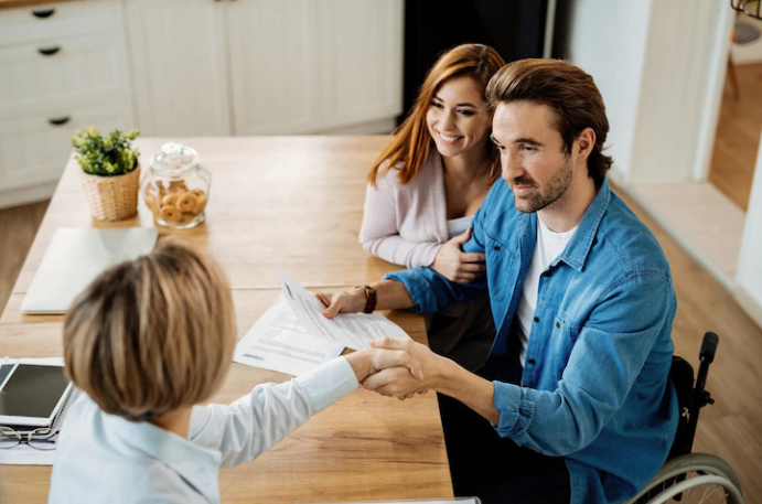 young couple shaking hands with real estate agent at home
