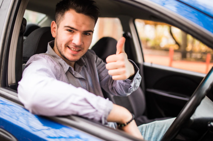 smiling man sitting inside car showing thumbs up