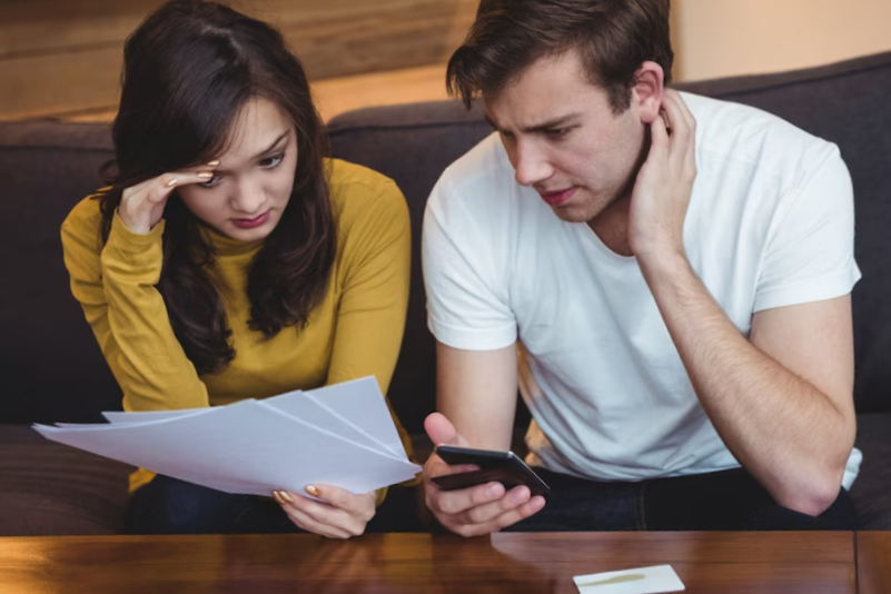 Couple sitting on sofa discussing with financial documents in living room