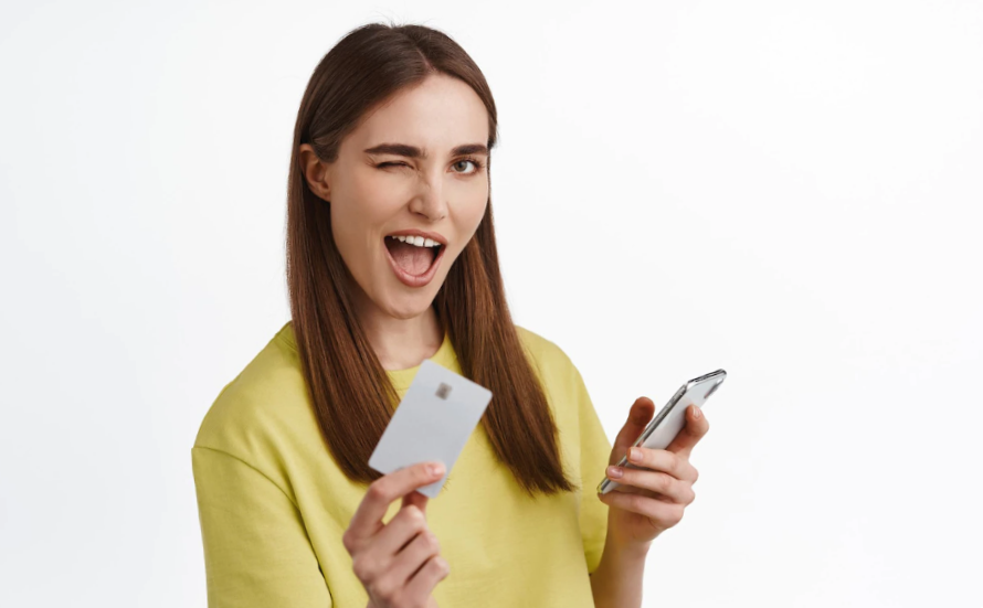 Cheerful girl showing credit card and winking