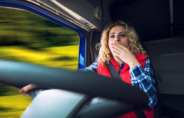 women yawning while driving a truck