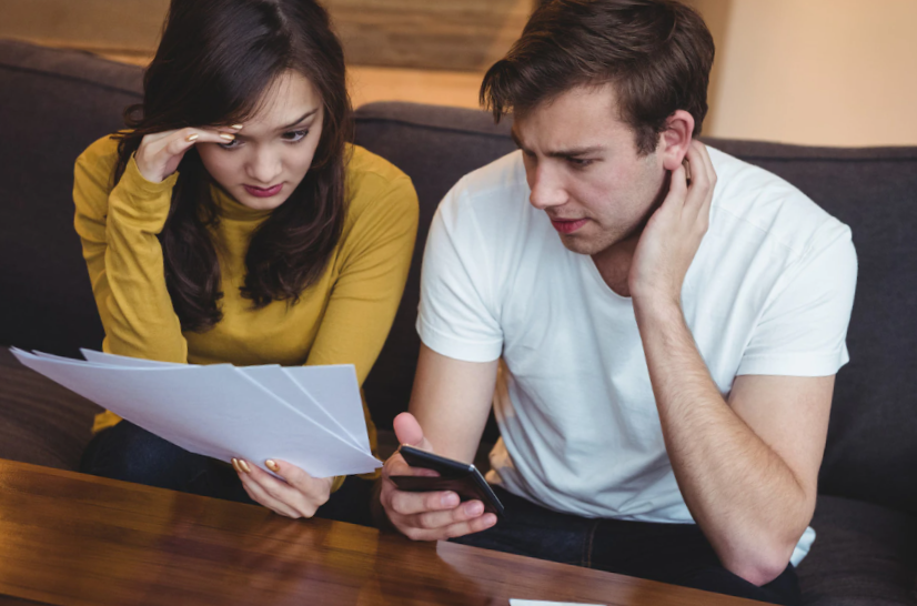 couple sitting on sofa discussing with financial documents in living room