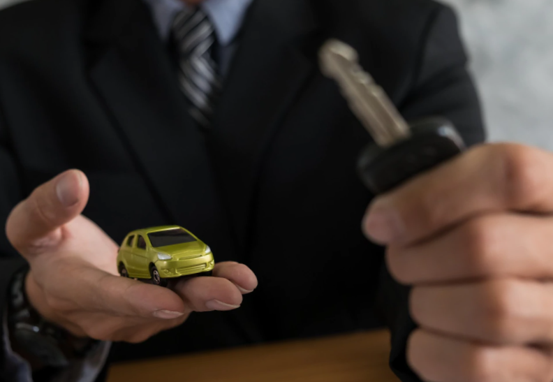 close up of man's hand holding a toy car and car keys