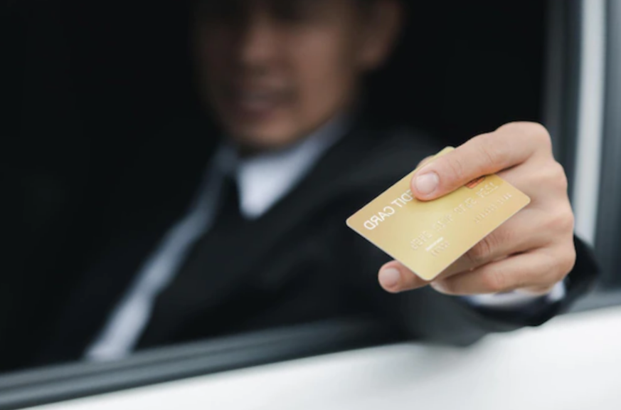 An asian man wearing a formal suit in the car handed his credit card through the window