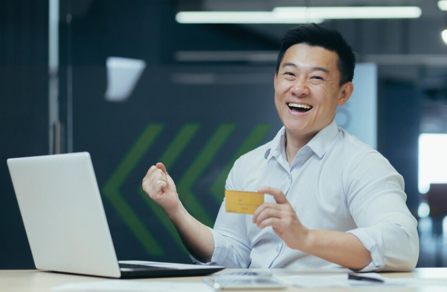Happy Asian businessman smiling and looking at camera holding credit card