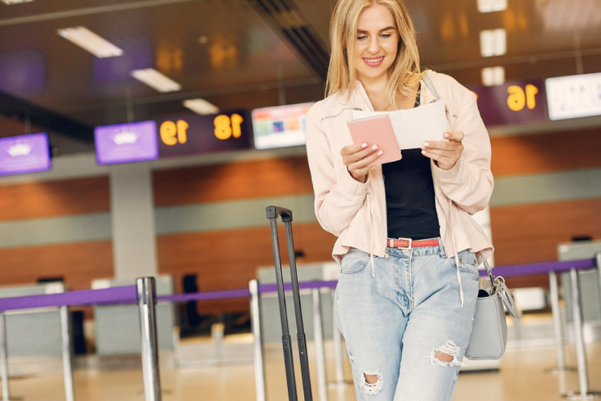 girl standing in airport reading boarding pass
