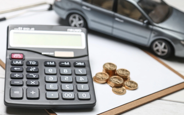 Car model,calculator and coins over a clipboard on white table

